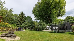 A grassy backyard with a trampoline, a wooden swing set, and a rock formation. - Apartment 'Hermanschau' with Shared Terrace, Shared Garden and Wi-Fi (Ühlingen-Birkendorf)