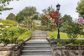 Una scala in pietra conduce a un arco in legno in un giardino.