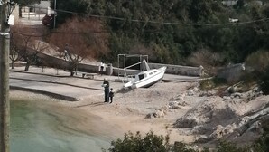 A boat docked at a rocky shore with a person standing nearby. - Seaside Apartments Sanda (Rogoznica)