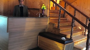 Een houten interieur met een receptiebalie, een trap en een bank.