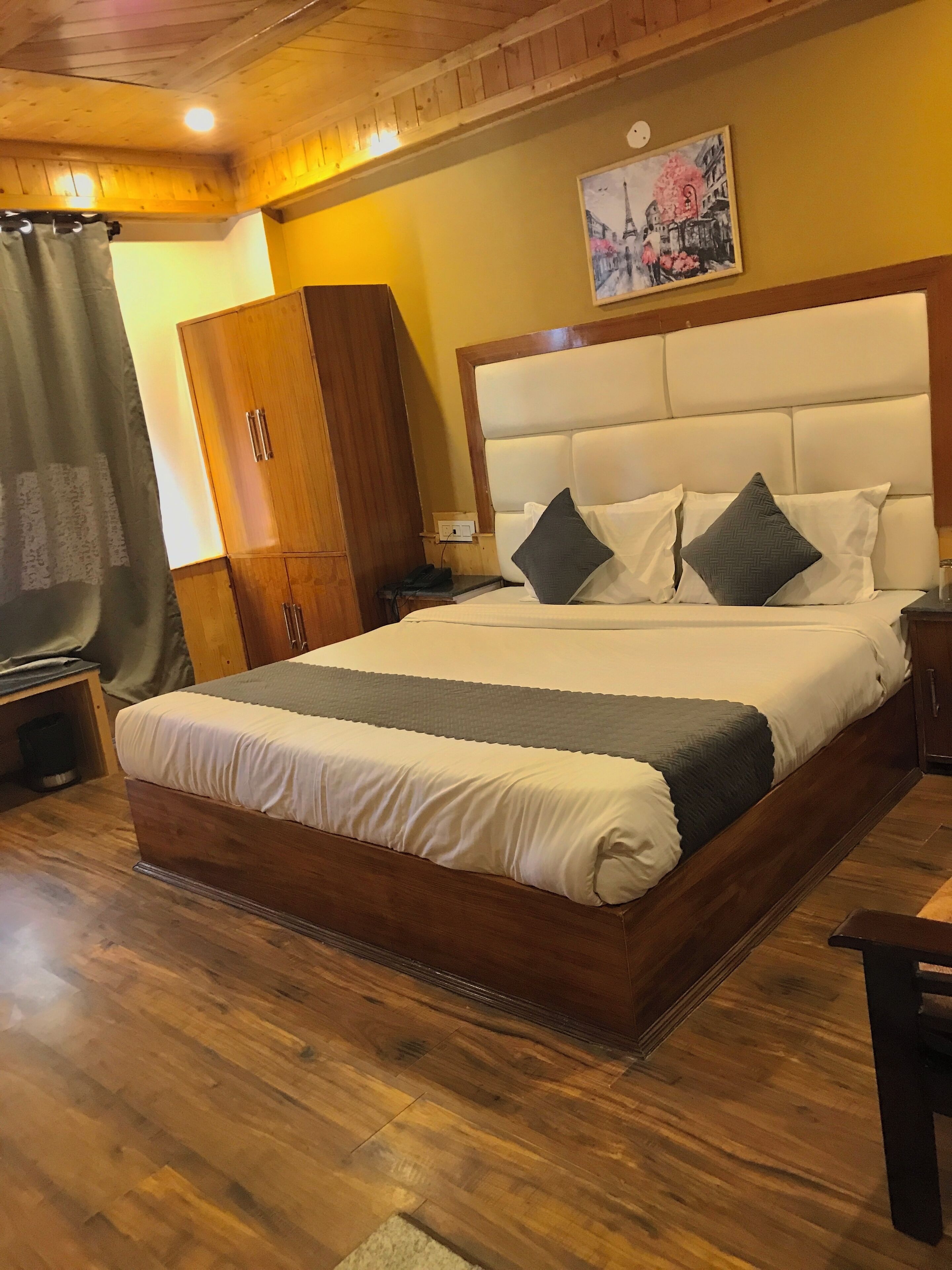 A bedroom with a wooden bed frame, a large headboard, and a nightstand with a lamp.