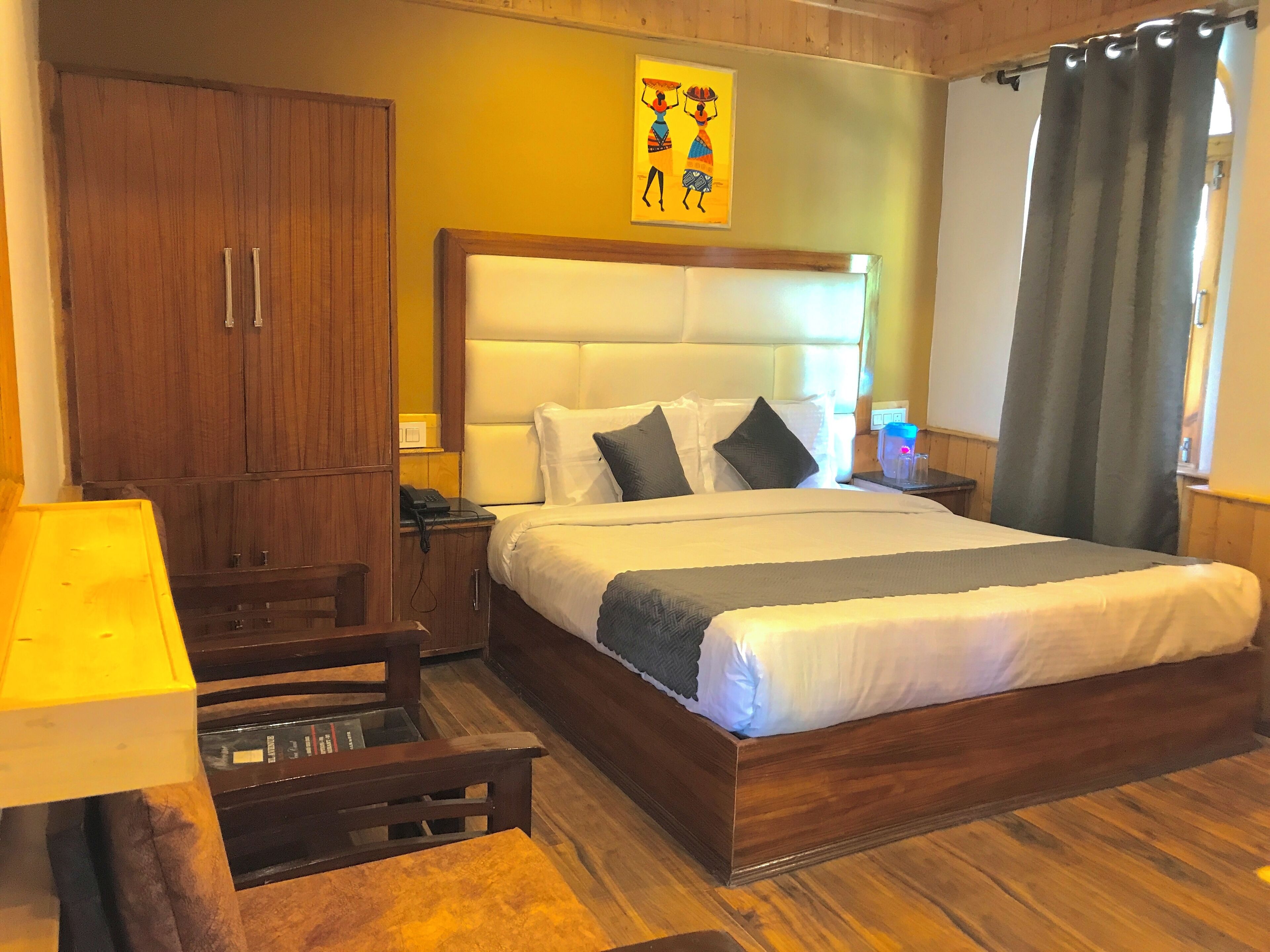Ein Hotelzimmer mit einem hölzernen Bett, einem Nachttisch, einem Schreibtisch mit Lampe und einem Kleiderschrank.