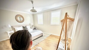 Un dormitorio con cama, mesitas de noche, un espejo y una silla colgante.