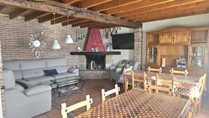 Una zona de estar acogedora con chimenea de ladrillo, muebles de madera y un televisor montado en la pared.