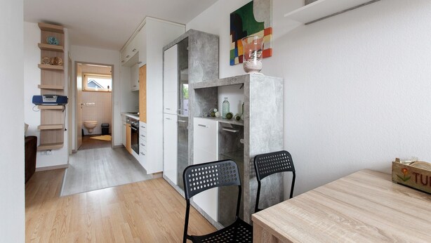 Una cocina moderna con una mesa y sillas de madera, horno empotrado y ventana con vistas.