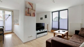 Una sala de estar con televisión, sofá y una mesita.