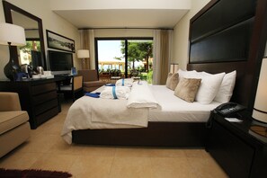 A hotel room with a bed, a desk, a TV, and a view of the outdoors. - Grand Tala Bay Resort (Aqaba)