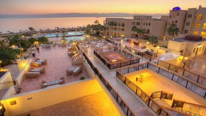 A rooftop terrace with outdoor seating, a pool, and a view of the sea at sunset. - Grand Tala Bay Resort (Aqaba)