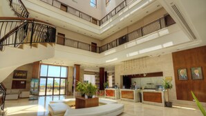 A spacious lobby with a curved seating area, a reception desk, and a staircase leading to upper floors. - Grand Tala Bay Resort (Aqaba)