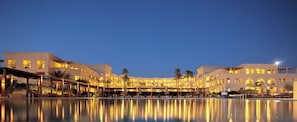 A hotel with a swimming pool, multiple balconies, and warm lighting. - Grand Tala Bay Resort (Aqaba)