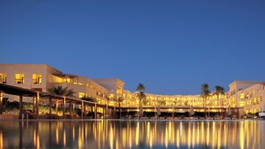 A hotel with a swimming pool, multiple balconies, and warm lighting. - Grand Tala Bay Resort (Aqaba)