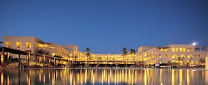 A hotel with a swimming pool, multiple balconies, and warm lighting.