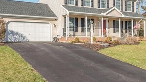 A two-story house with a garage, a covered porch, and a well-maintained lawn.