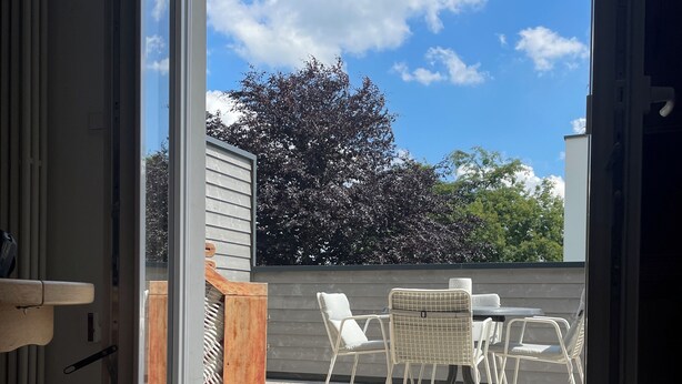 Ein Zimmer mit einer Schiebetür zu einer Terrasse im Freien, ausgestattet mit Tisch und Stühlen.