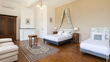 Une chambre d’hôtel avec deux lits, un coin salon avec un canapé, une petite table et un tapis à motifs.