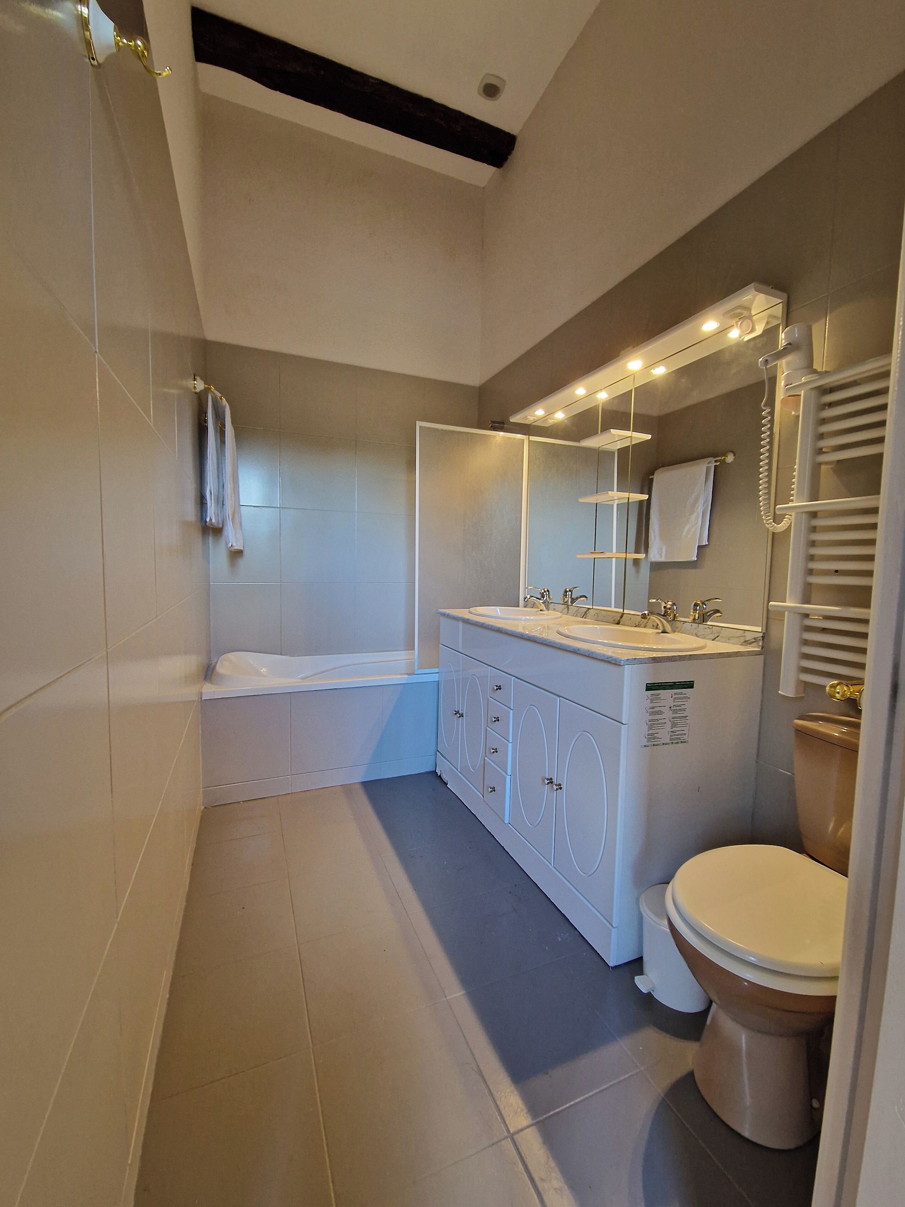 A modern bathroom with a bathtub, double sinks, and a toilet.