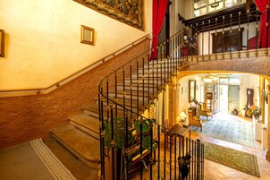 Una amplia escalera con barandillas ornamentadas que lleva a un balcón en el segundo piso.
