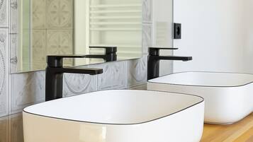 Une salle de bain moderne avec deux vasques blanches, des robinets noirs et un grand miroir placé au-dessus.
