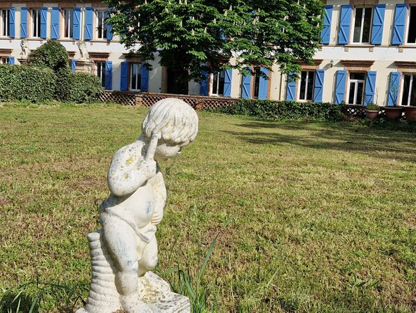 A statue of a child in a grassy area with a building in the background.