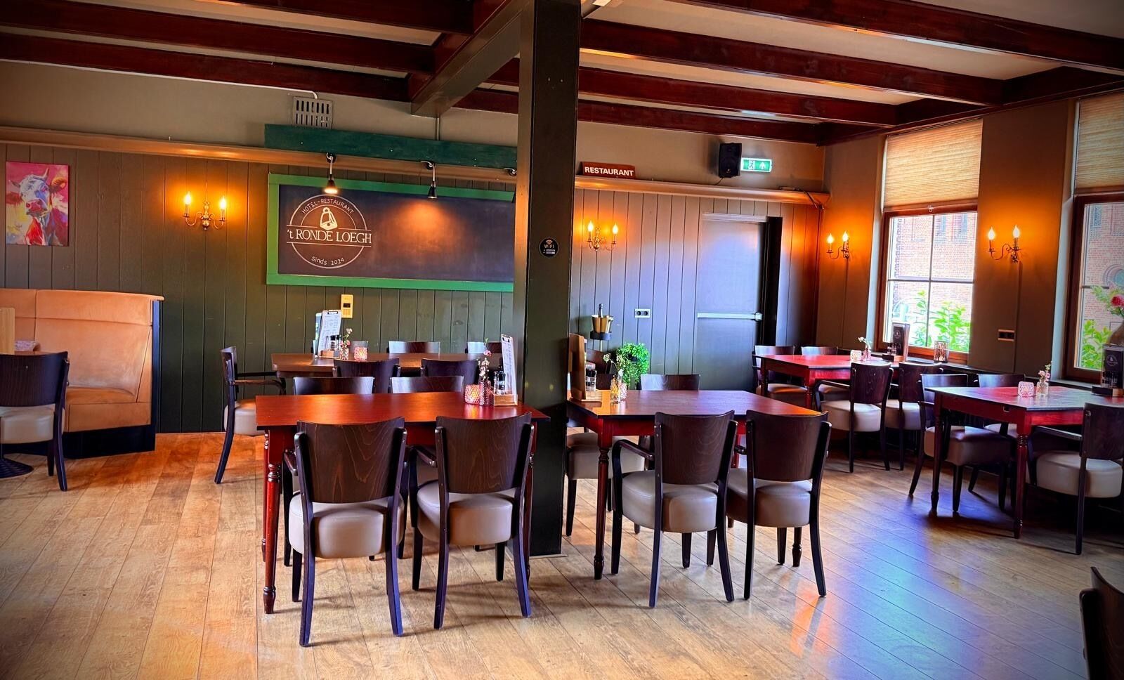 A restaurant interior with wooden tables and chairs, a counter, and a sign indicating it's a restaurant.