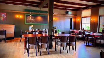 A restaurant interior with wooden tables and chairs, a counter, and a sign indicating it's a restaurant.