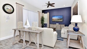 Un salon avec un canapé, une table basse, un téléviseur et un ventilateur de plafond.