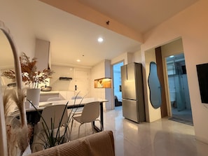 A modern kitchen with a dining area, a refrigerator, and a TV mounted on the wall.
