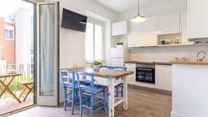 Een moderne keuken met witte kasten, een houten eettafel, blauwe stoelen en een inbouwoven.