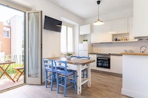 Una cocina moderna con armarios blancos, una mesa de comedor de madera, sillas azules y un horno empotrado.