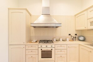 Une cuisine dotée de meubles en bois, d’une cuisinière à gaz, d’un four et d’une hotte aspirante en acier inoxydable.
