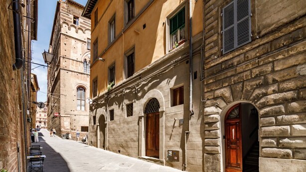 Una calle estrecha con edificios históricos, fachadas de piedra y arcos.