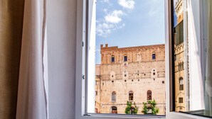Una ventana con vista a un edificio histórico con múltiples ventanales y cielo despejado.