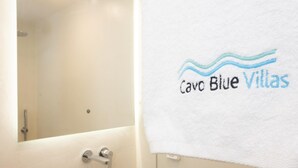 Ein Badezimmer mit Marmorwaschbecken, einem Spiegel und einem Handtuch mit dem Aufdruck 'Cavo Blue Villas'.