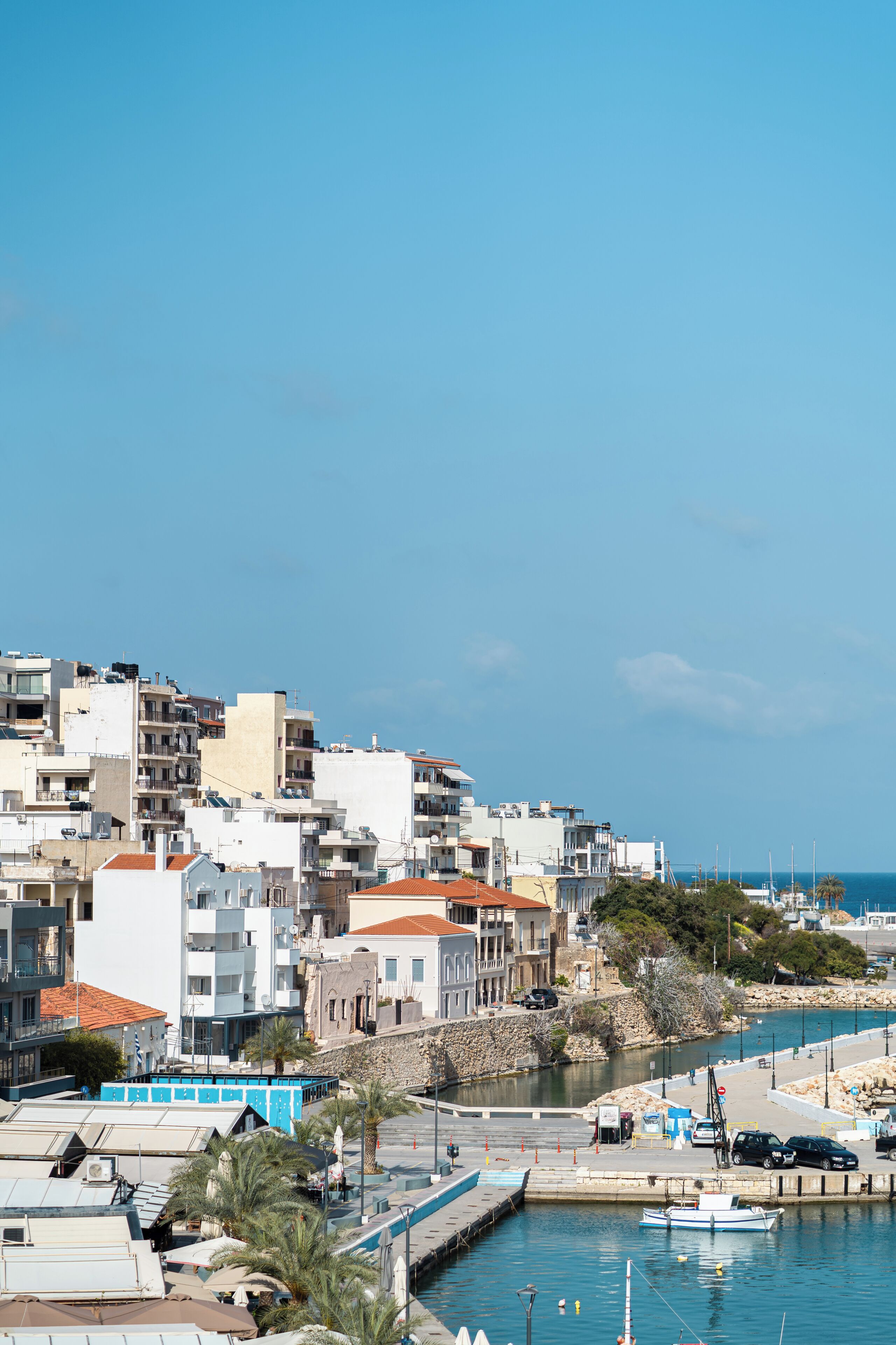 A coastal cityscape with buildings, a marina, and a clear sky.