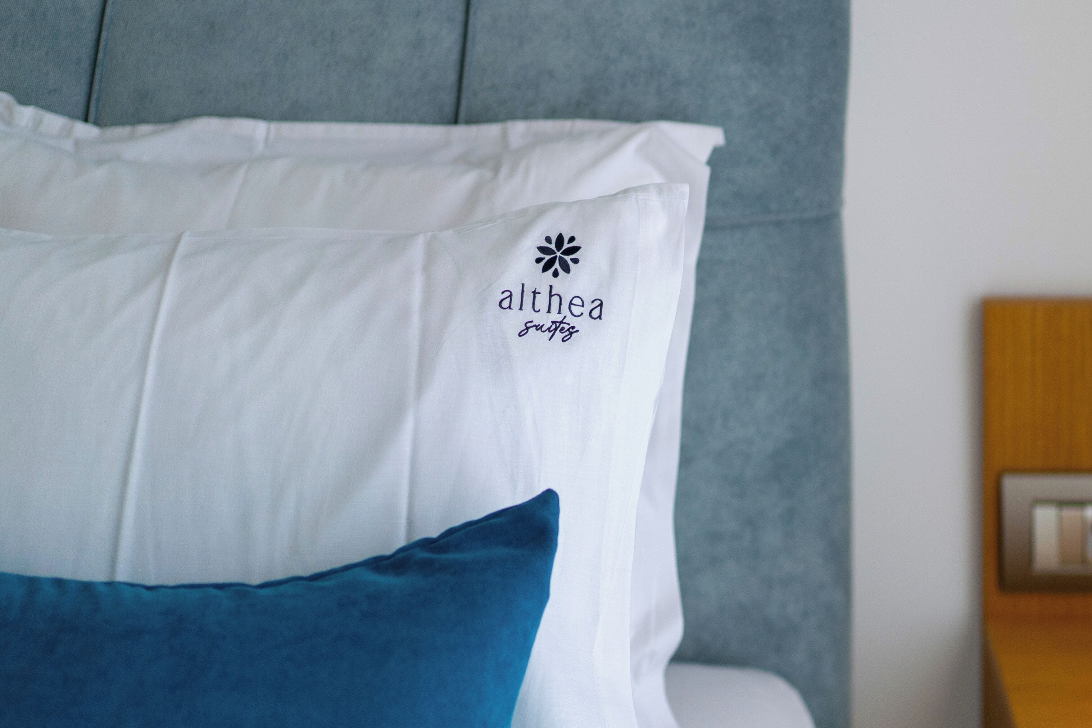 A bed with a white pillow featuring the logo "althea spas" and a blue pillow.