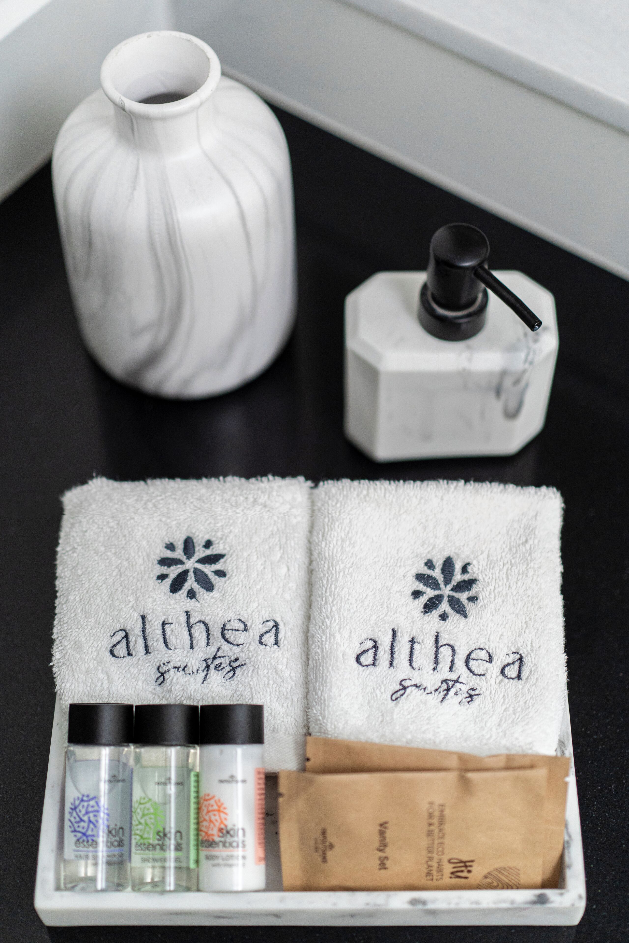 A bathroom vanity with a white vase, a soap dispenser, and a towel rack.