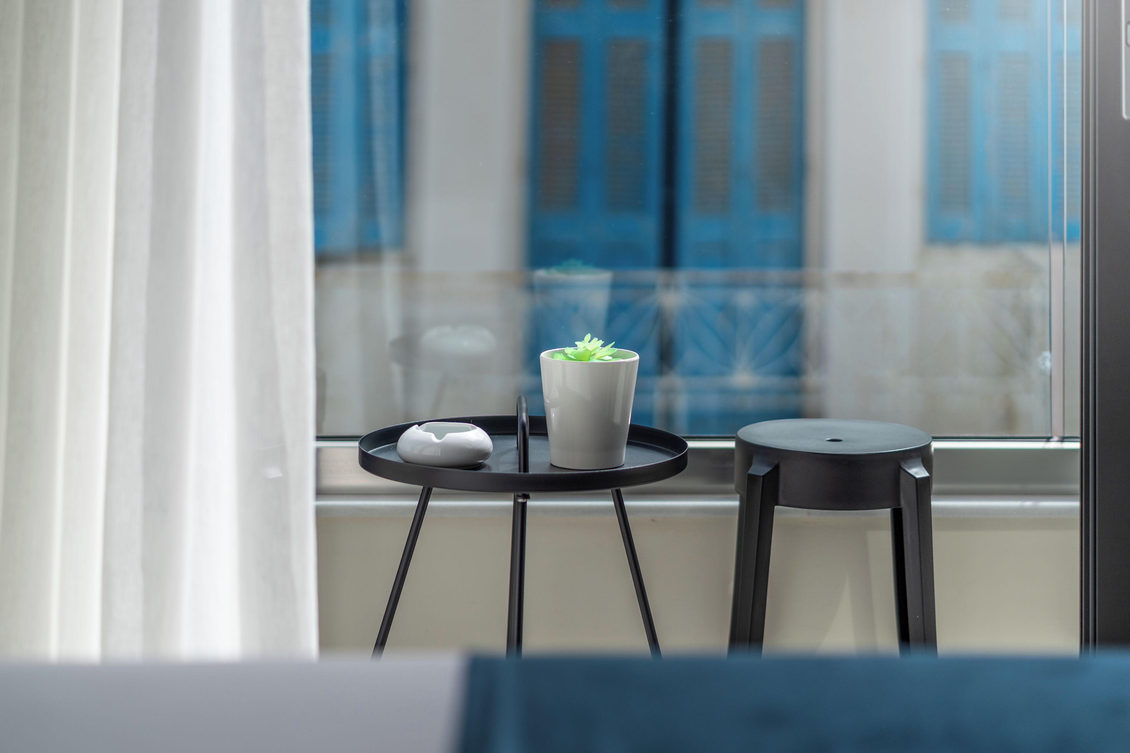 A modern room with a small black table, a white vase with a plant, and a white object on the table.