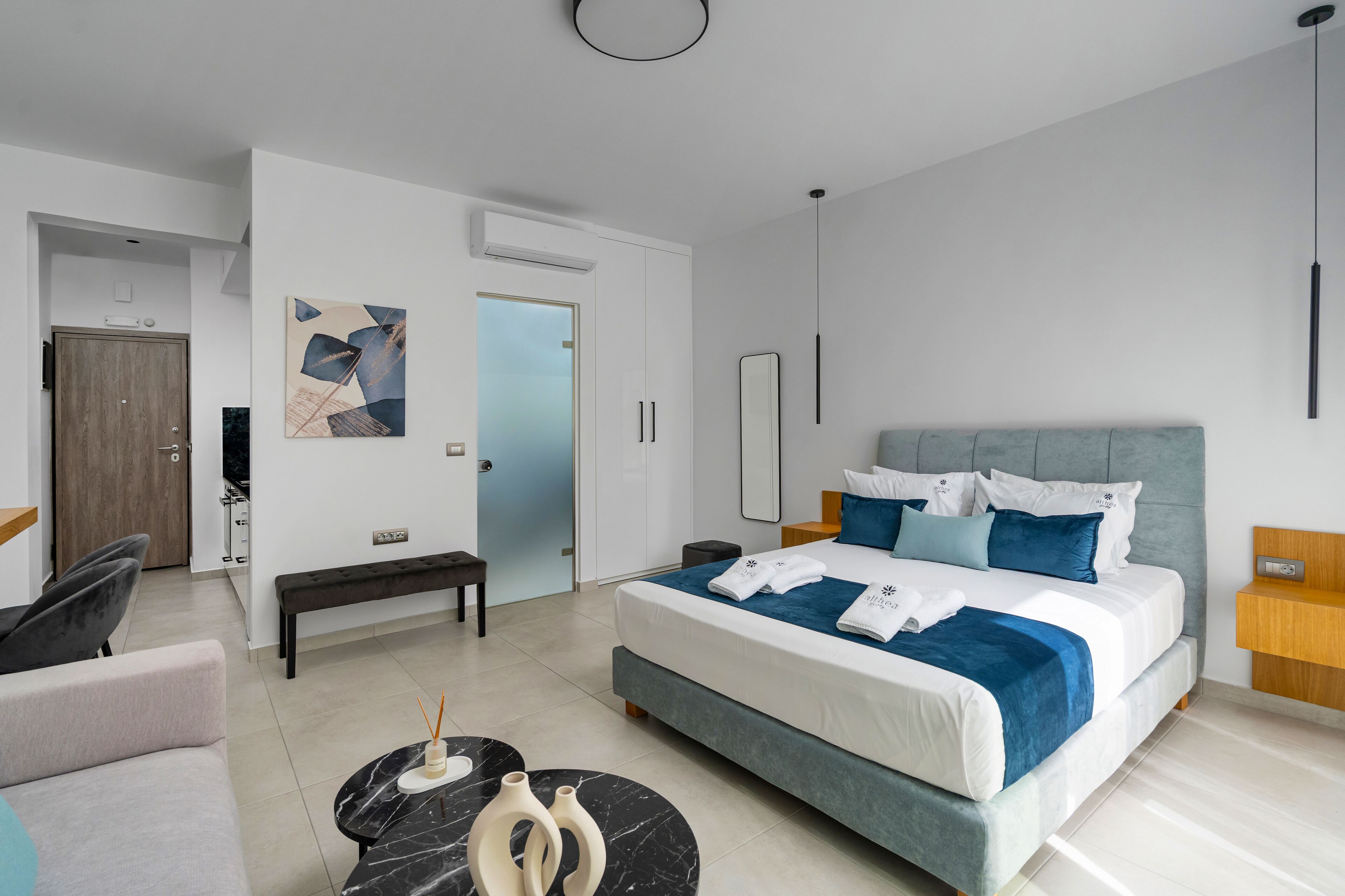 Una habitación de hotel moderna con una cama grande, un banco, un sofá y un escritorio.