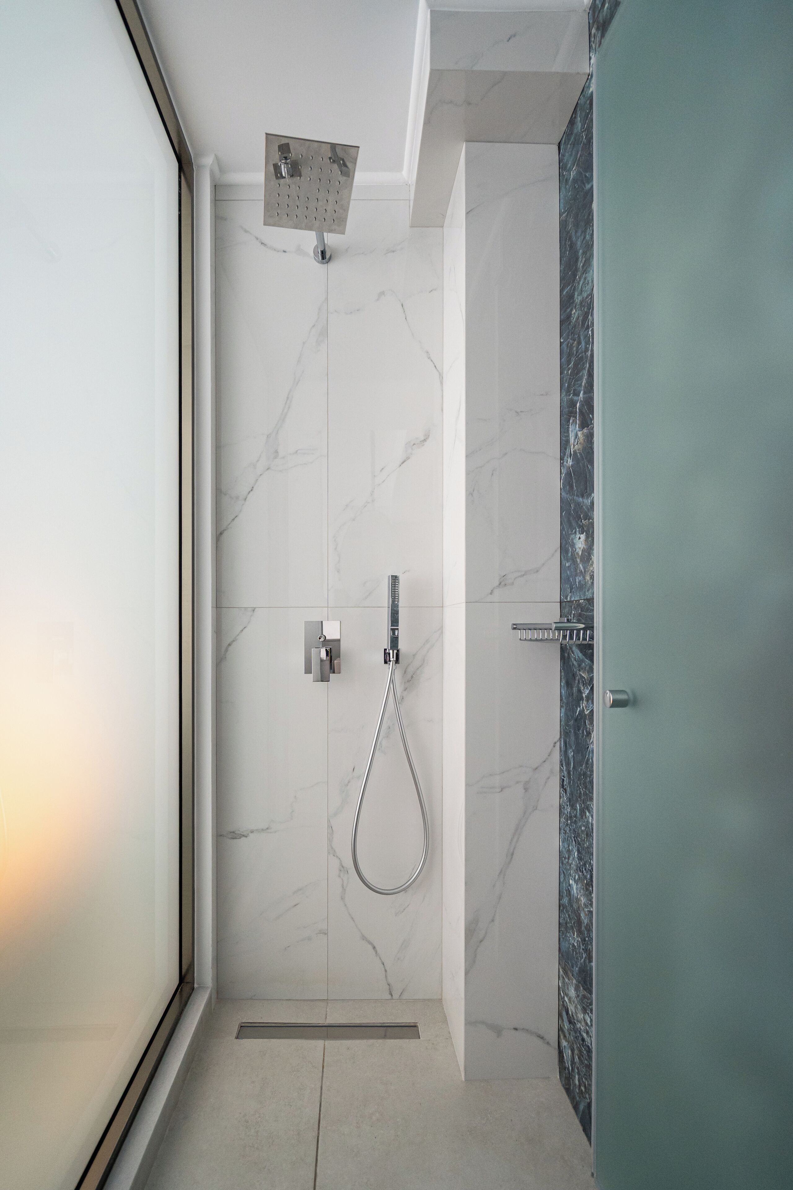 A modern shower with a handheld showerhead and a wall-mounted control panel.