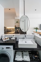 Un baño moderno con un espejo grande, un lavabo y una lavadora.
