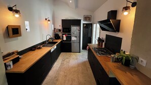 A modern kitchen with black cabinets, a wooden countertop, a built-in stove, and pendant lighting.