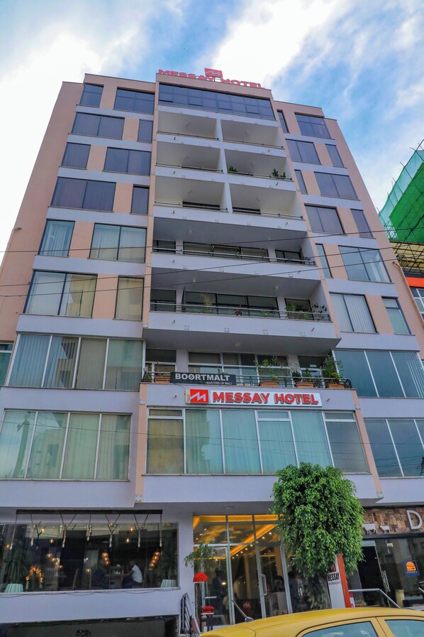 Un edificio a più piani con un cartello che indica 'MESSAY HOTEL' e 'BOORMALT' al piano terra.