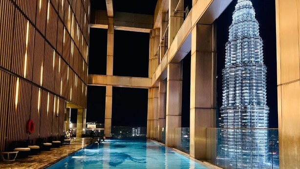 Ein Innenpool mit Blick auf die Petronas Towers bei Nacht.