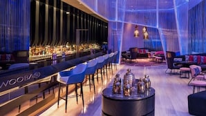Ein moderner Loungebereich mit Bar, Sitzgelegenheiten und Blick auf die Stadtlandschaft.