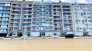 A multi-story residential building with balconies, a gated entrance, and a paved area in front. - Seaview Apartment in Nieuwpoort (Nieuwpoort)