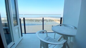 A balcony with a view of a beach and a pier, a white table, and a white chair. - Seaview Apartment in Nieuwpoort (Nieuwpoort)