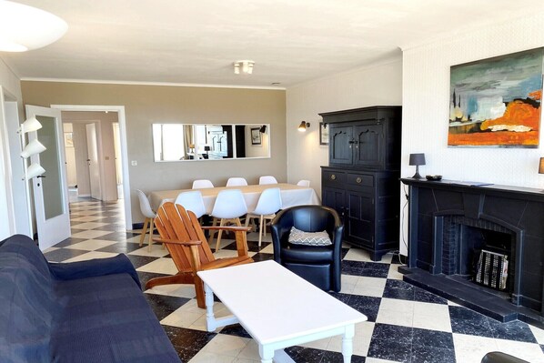 Ein Wohnzimmer mit Schachbrettboden in Schwarz und Weiß, einer schwarzen Ledersofa, einem weißen Tisch und einem Kamin.