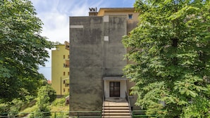 Un edificio de varios pisos con fachada de concreto, una escalera central y una puerta de entrada pequeña.