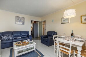 A living room with a sofa, a dining table set for two, and a refrigerator in the background. - Seaview City Apartment Frida (Rijeka)