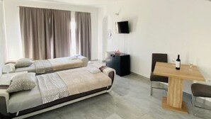 A modern hotel room with two single beds, a wooden dining table, and a TV mounted on the wall. - Villa Brazza (Milna)